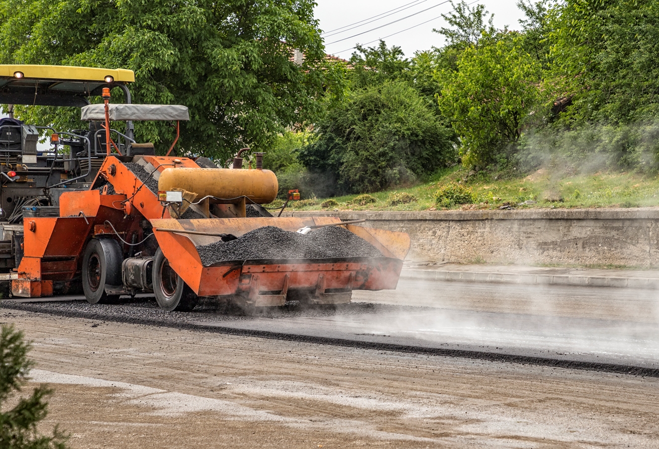 Asphalt paver machine makes a new road and repairing works. A paver finisher, asphalt finisher or paving machine placing a layer of asphalt. Repaving.