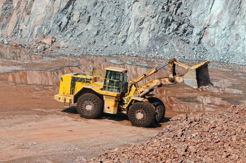 A large yellow and black truck is parked in the dirt